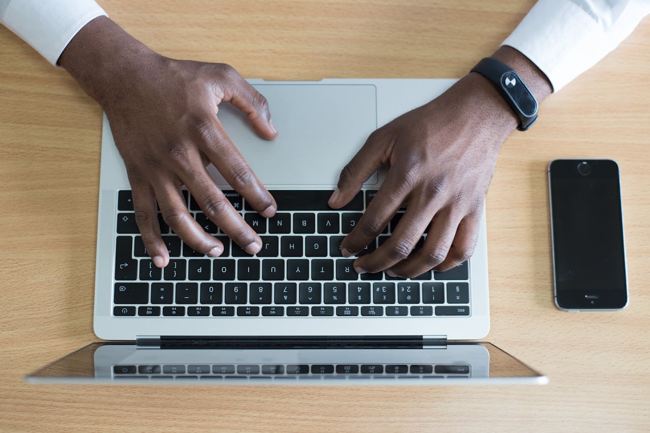 our-story Person typing on a laptop with a smartphone nearby, showcasing modern technology use.